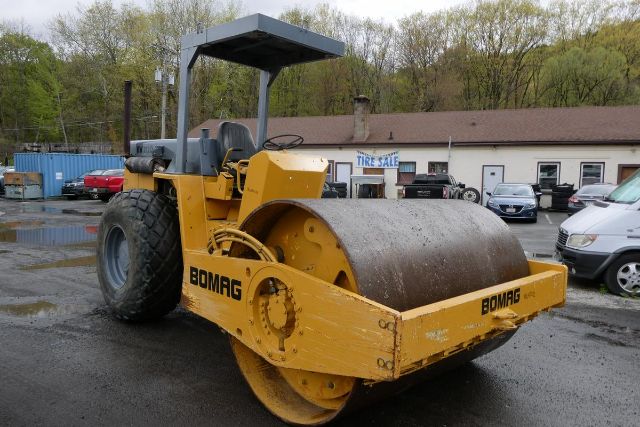  Bomag BW212D-2 roller compacting drum with yellow paint, operator seat, and canopy frame in an outdoor lot.