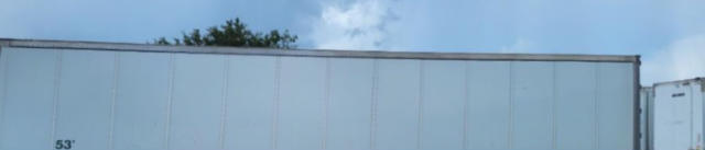 Trailer side with plain metal panel and small lettering faded; part of a Vanguard VXP trailer.
