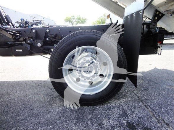 Ford F-550 dump truck wheel and chassis showing front wheel with steel rim and tire, underbody components and dump bed side panel.