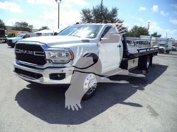Ram 5500 tow truck chassis with flatbed, white front grille showing RAM badge, large dual rear wheels, and extended cab.