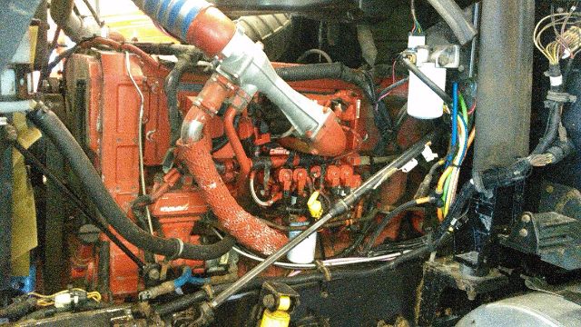 Engine bay of a 2007 International 9900i showing red engine with hoses, wiring, and various components.