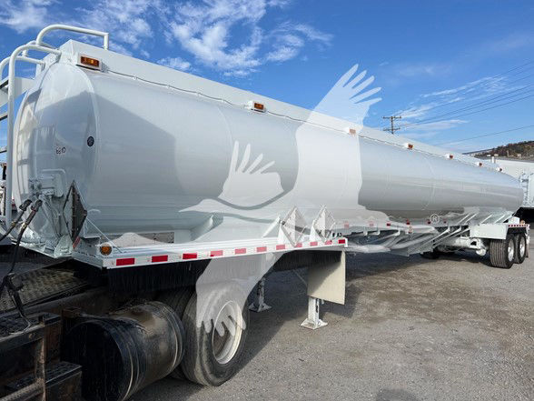 Tank trailer showing large cylindrical white Heil 9200 gallon trough bottom petro tank with multiple access hatches, ladder, and support legs.