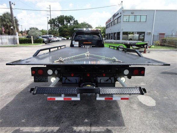 Ram 5500 tow truck rear with flatbed and safety chains, rear lights, and bumper brackets.