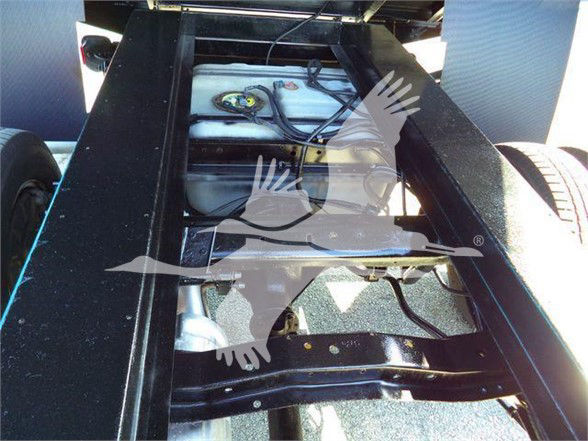 Ford E450 chassis area showing fuel tank and frame rails in a dump truck configuration.