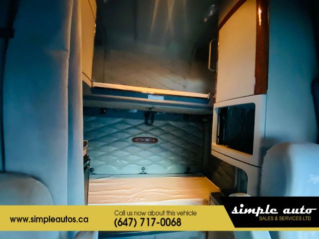 Cab interior photo of a 2012 Freightliner Cascadia sleeper area with quilted blue sleeper wall, storage cabinets, and a yellow banner overlay at bottom. Visible text: simpleautos.ca, Call us now about this vehicle (647) 717-0068, simple aut