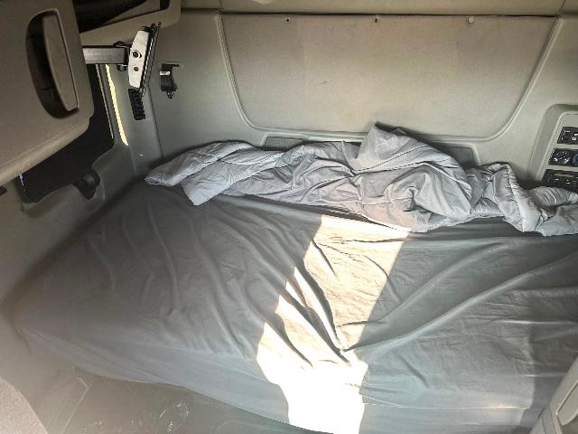 Interior sleeper cab bed in a used 2017 International Prostar tractor with a neatly spread bed cover and windowless side panel.