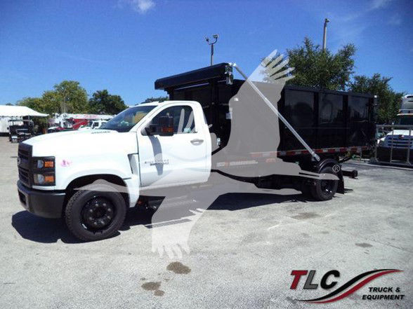 Front left view of a white Chevrolet Silverado 6500HD dump truck with a black dump bed in a dealership lot. TLC Truck & Equipment logo watermark.