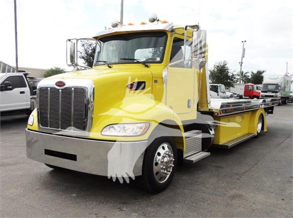 Yellow 2022 Peterbilt 337 tow truck side view showing front grille, headlights, chrome bumper, and flatbed with side steps.