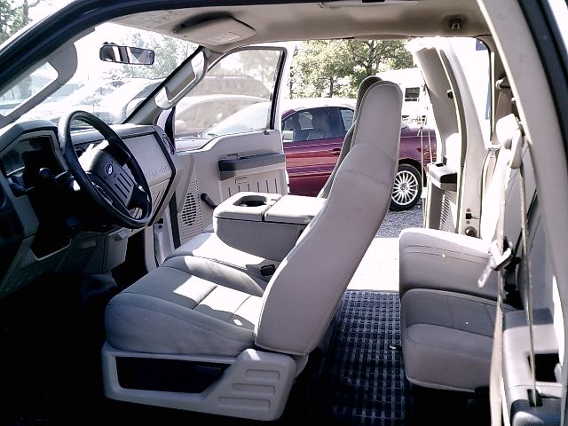 Interior of a 2008 Ford F-250 Super Duty crew cab with light gray seats, front bench seat, and open doors; steering wheel, dashboard, and center console visible.