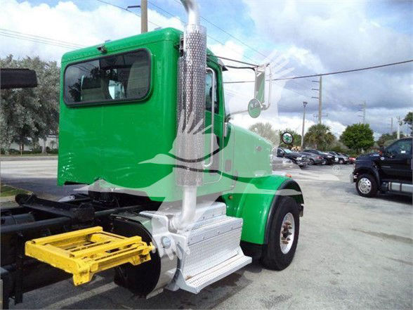 Green Peterbilt 367 rear side view showing cab, exhaust stack, and yellow rear hitch platform.