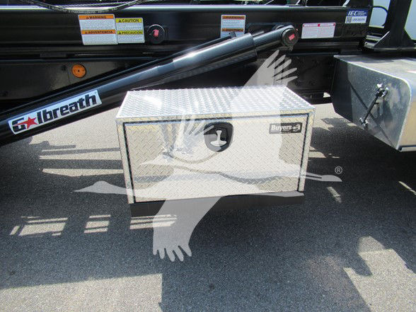 Silver diamond-plate tool box mounted on a truck bed with a black bed rail and a white decal in the background.