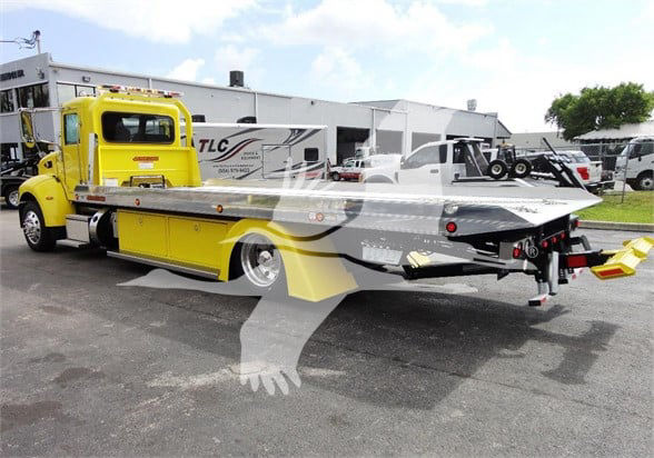 2022 Peterbilt 337 tow truck with bright yellow cab and aluminum flatbed, side storage compartments, rear winch and multiple lights visible.