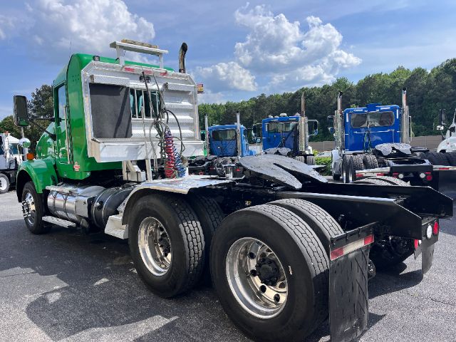 Kenworth T800 low-bed tractor rear view showing dual rear axles and fifth-wheel, green cab with polished aluminum fuel tanks and chrome exhaust stacks.