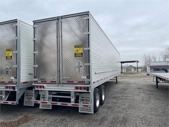 Trailer dual-axle CIMC Cool Globe reefer van with silver diamond-plate doors, rear doors closed, warning stickers, and support legs visible.