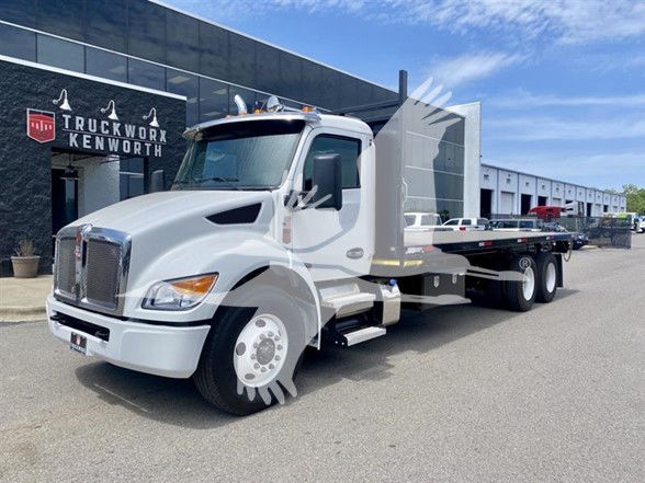 Kenworth T480 flatbed truck in white, front three-quarter view, parked outdoors near a dealership. visible VIN/stock details in listing text.