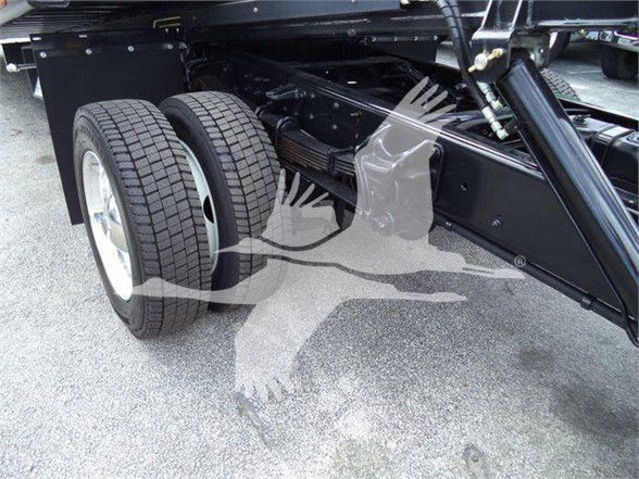 Dual rear wheels on a truck chassis showing the suspension and frame, with a painted black chassis and components.
