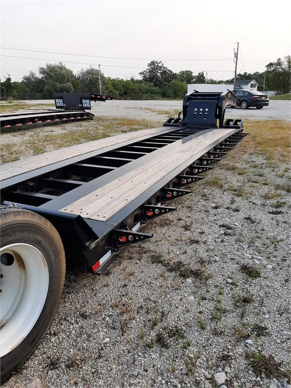  Fontaine 55 ton lowboy trailer with long steel deck and ramp fixture, black paint, tandem axle wheel in foreground, gravel lot background.