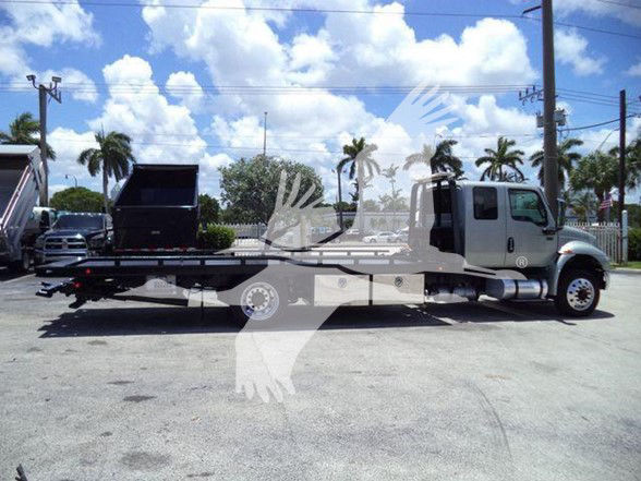 Tow truck with extended flatbed and wheel-lift on trailer; white cab and gray flatbed truck with hydraulic tilt.