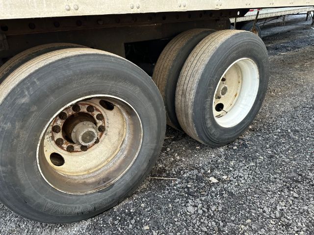 Dual rear wheels of a utility trailer with steel rims and black tires. Side of trailer undercarriage visible.