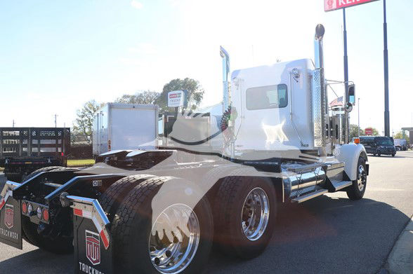 Kenworth W900L conventional daycab tractor truck rear and side view showing chrome wheels, dual rear axles, and sleeper cab with white exterior.