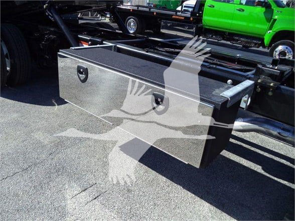 Ford F750 SD tow truck chassis with a long black aluminum toolbox mounted on the side of the frame, visible with a trailer hitch and truck in background.