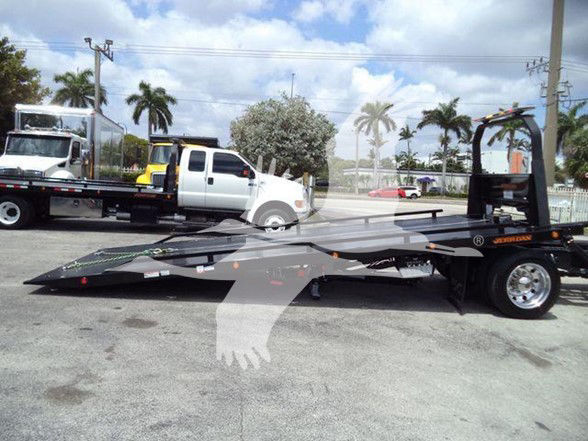 2018 Peterbilt 337 tow truck with low-profile car hauler trailer in a lot.