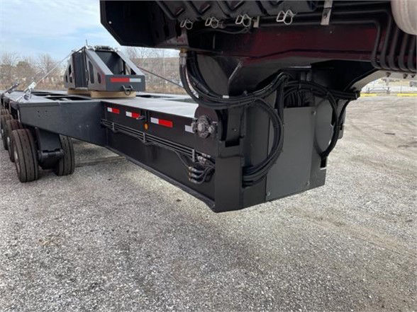 Trailer frame and deck with hydraulic landing gear and hoses visible, lower view showing black steel components and wiring along the trailer chassis.