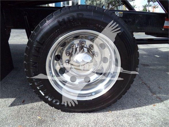 Tow truck wheel with chrome rim and black tire mounted on Kenworth T280 chassis showing wheel detail.