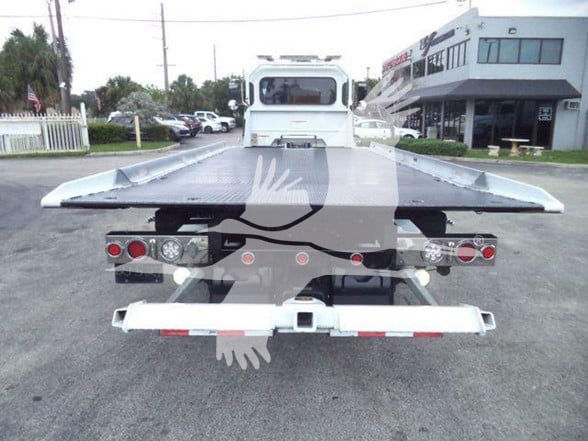 Tow truck flatbed rear view with platform bed and tail lights visible.