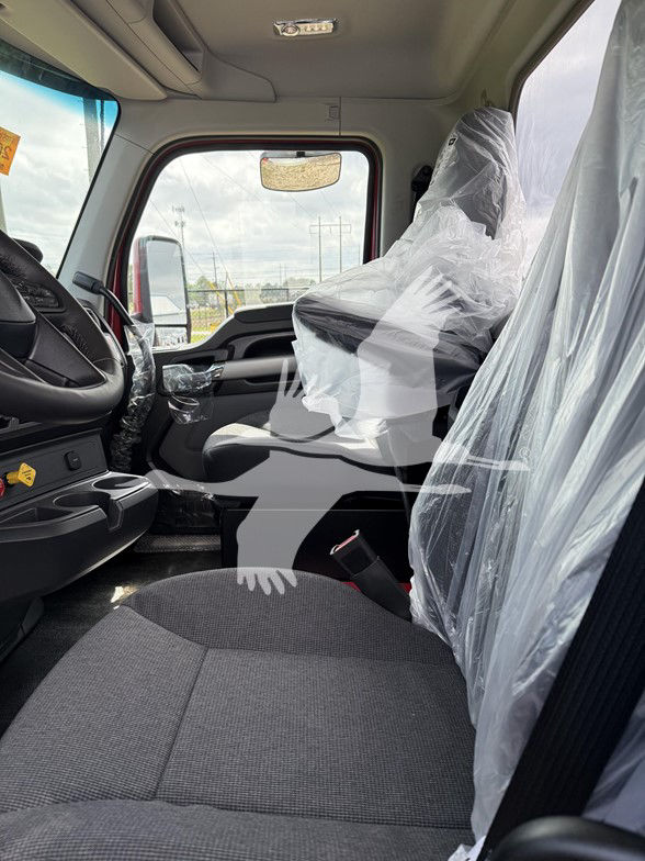 Kenworth T880 interior cabin view with driver seat and passenger seat wrapped in plastic; steering wheel and dashboard visible.