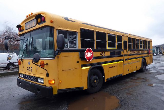Yellow Bluebird All American school bus with stop sign extended and number 455 on side, front view, in a lot.