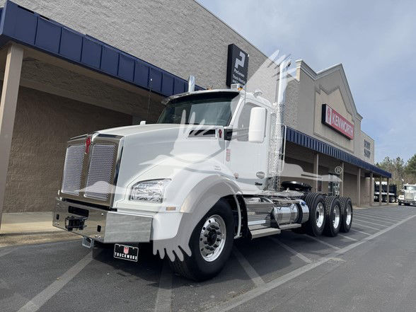 Kenworth T880 conventional daycab tractor in white with chrome grille and dual rear axles, parked outside dealership.