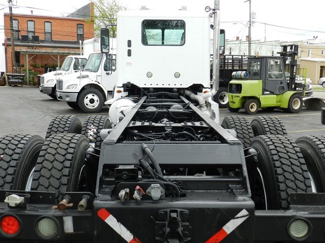 Cab and chassis truck rear chassis frame with tandem axles and dual rear wheels in a yard.