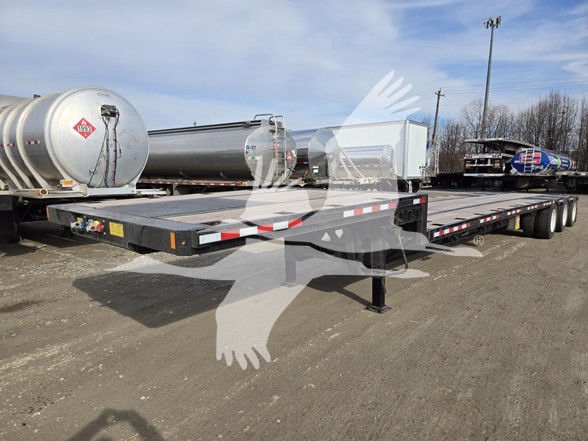 Tri-axle steel drop deck trailer in an outdoor yard with other trailers and tanks nearby.
