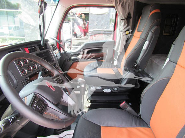 Kenworth W990 truck interior showing steering wheel, dashboard, and orange/gray seats in the cab.