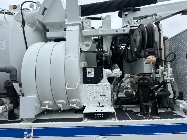 Truck chassis of a Freightliner 114SD vacuum service unit with hoses, reel, and hydraulic components visible.