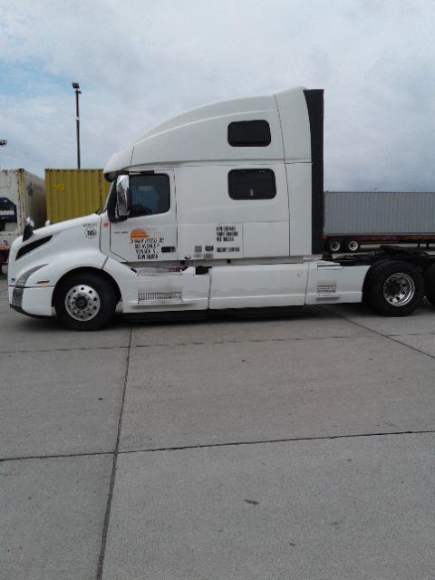 Truck side view showing a white 2019 Volvo D13 conventional sleeper tractor with company text on door and various service decals.