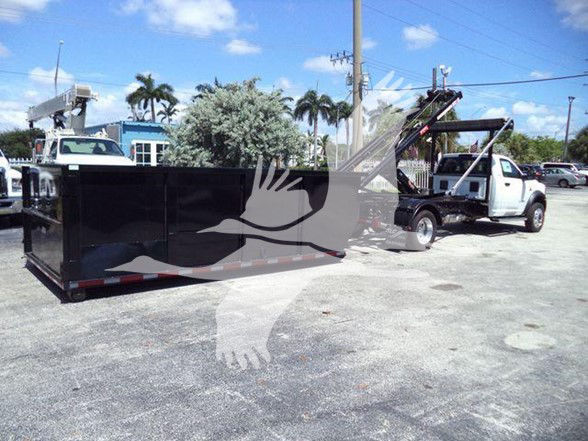 Ram 5500 HD SLT dump truck with a long black dump bed and hydraulic lift, rear view showing front cab and towing setup.