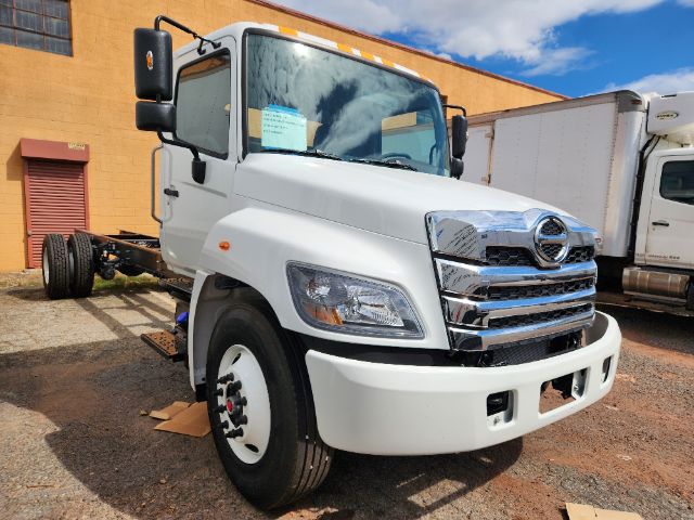 2025 Hino L6 cab chassis truck front view showing white cab, chrome grille, and large side mirrors.