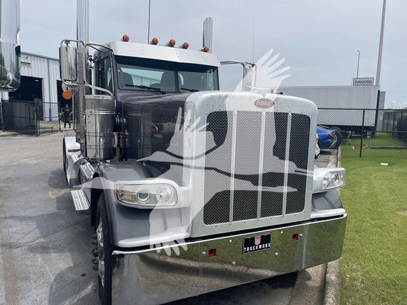 Peterbilt 389 truck front view showing chrome grille and bumper, dual large headlights, top cab lights, and side mirrors.