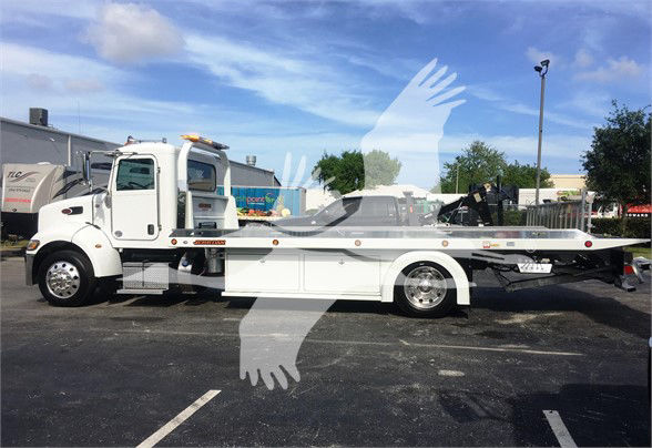 Peterbilt tow truck side view showing flatbed, white cab, chrome wheels, and warning lights. Visible text includes 'Peterbilt' on the door and 'Tow' category context; appears as a new 2022 model with stock number J51806.