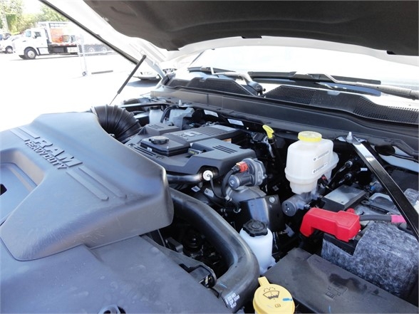 Ram 5500 HD engine bay showing cold air intake, brake fluid reservoir, power steering components, and battery with red positive terminal cover.