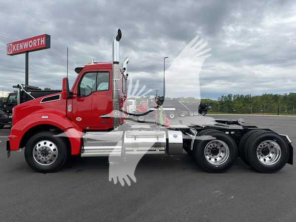 Kenworth T880 conventional daycab tractor in red, side view showing chrome fuel tanks and dual rear axles.