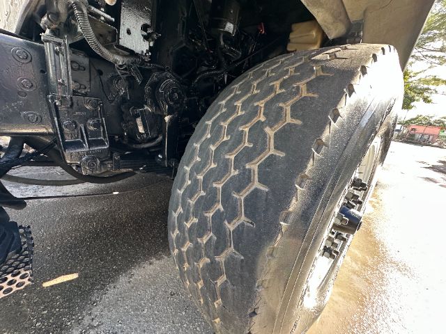 Truck front wheel and suspension components with large treaded tire and black chassis visible.