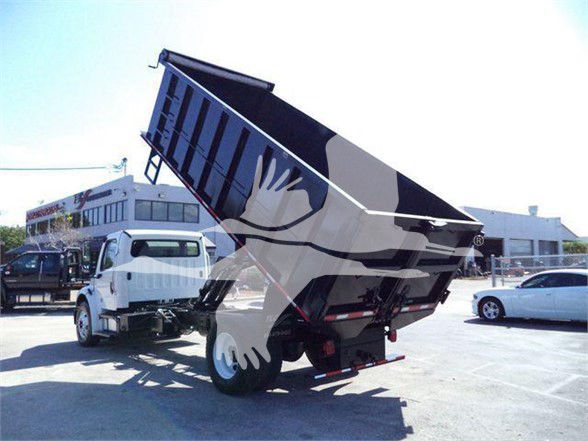Dump truck with raised bed in a dealership lot, Freightliner business class M2 106 chassis visible in background.
