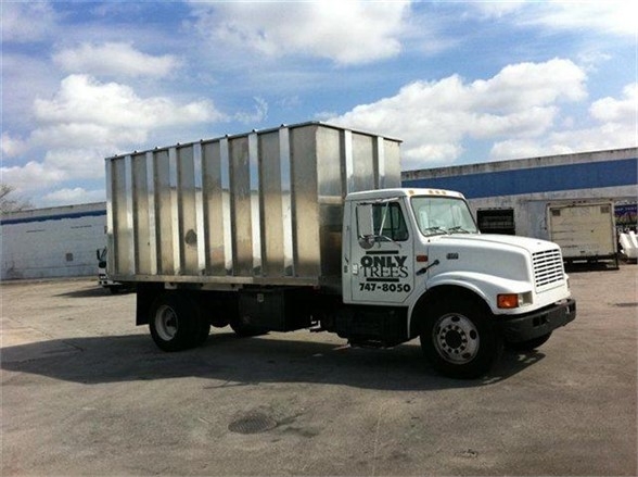 Truck with a large metal dump body attached, white cab with 'ONLY TREES' logo, 16 ft dump body mounted on a heavy-duty chassis.