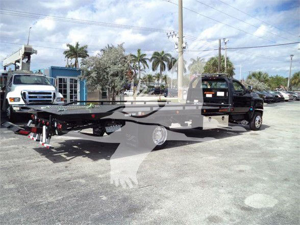 Tow truck with flatbed from side showing VIN and stock on truck lot.