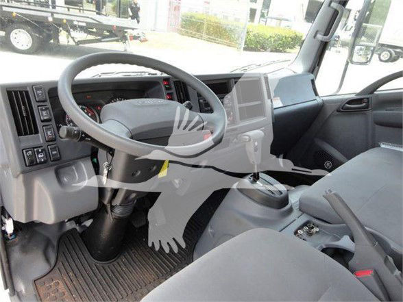 Isuzu NRR truck interior showing steering wheel, dashboard, gear shifter, and driver seat with multiple control panels.