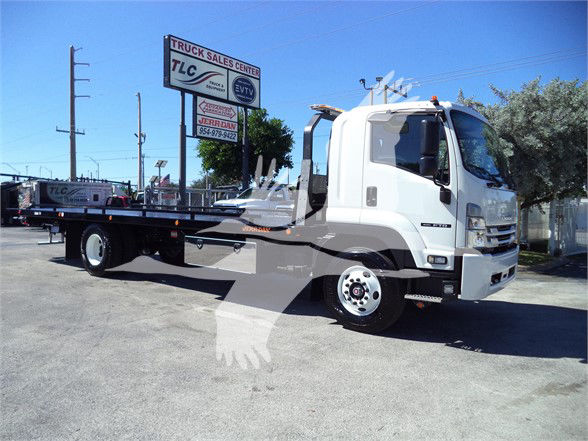 Isuzu FTR tow truck in a dealership lot with a flatbed, cab white, side view.