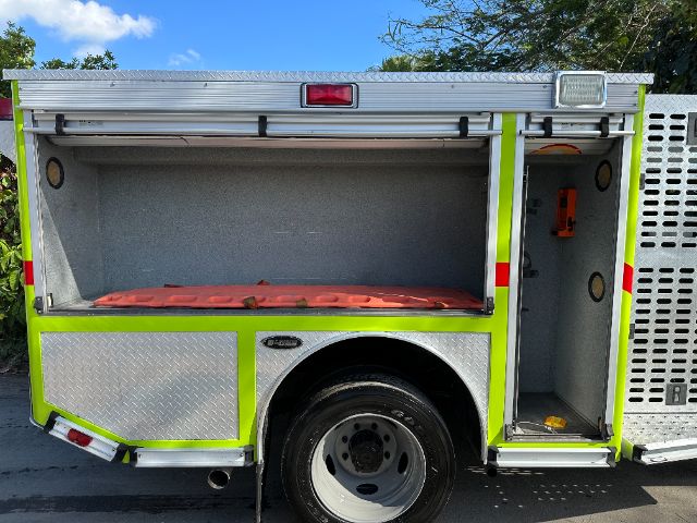 Ford F-550 fire rescue truck side compartment open showing storage area and wheel well.